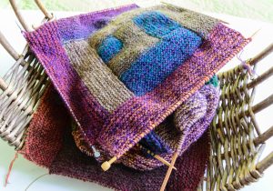 Close-up background image of a variegated knitted blanket with a colorful graphic design, crocheted, knitted plaid in a variegated style, knitted squares with a different pattern